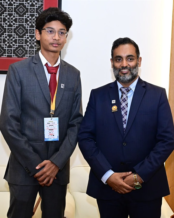 Tata Maithrinath in a suit and summit badge, standing beside a guest in a navy suit at the PanIIT summit.