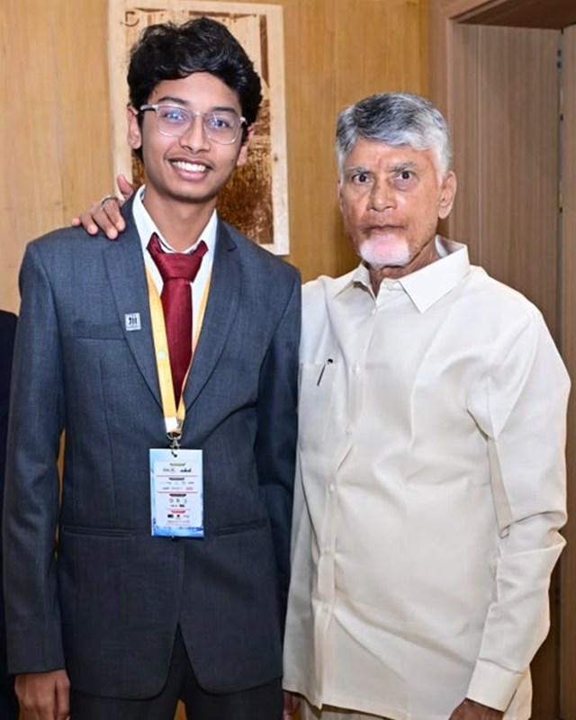 Tata Maithrinath in a suit and summit badge, smiling beside Nara Chandrababu Naidu, Chief Minister of Andhra Pradesh, at the PanIIT summit.